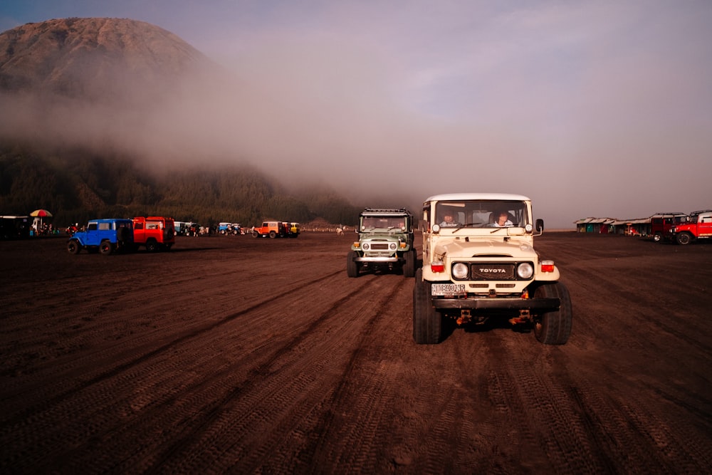 a group of vehicles driving on a dirt road