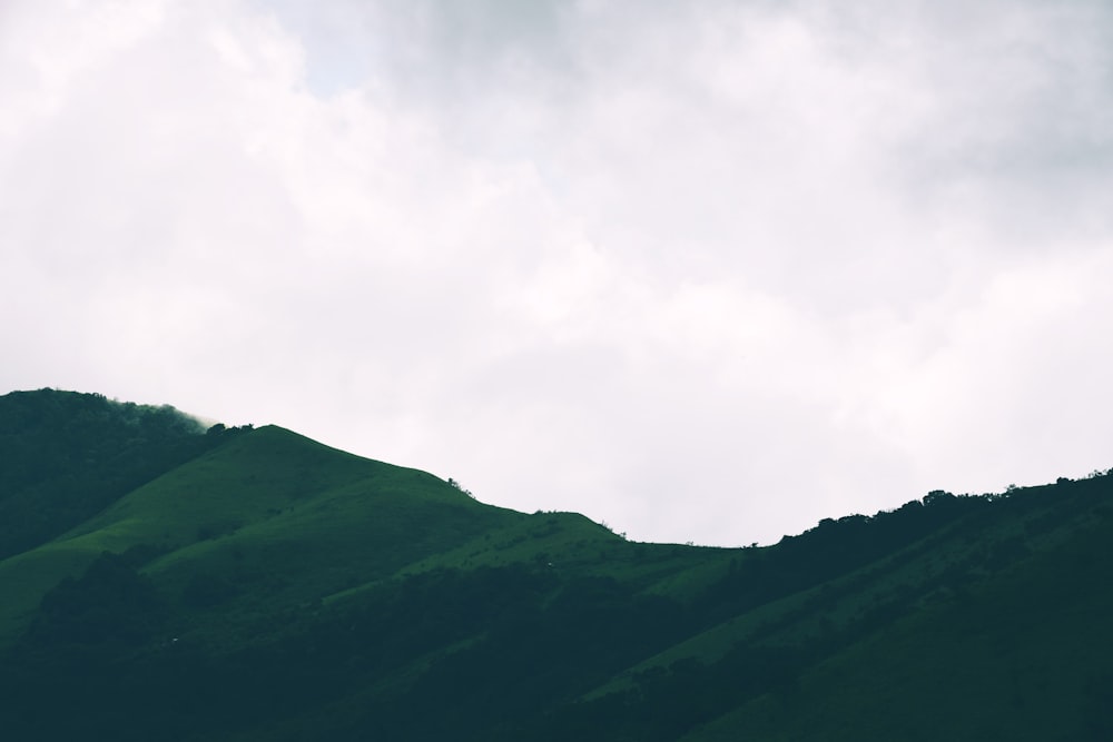 a green hill with clouds above