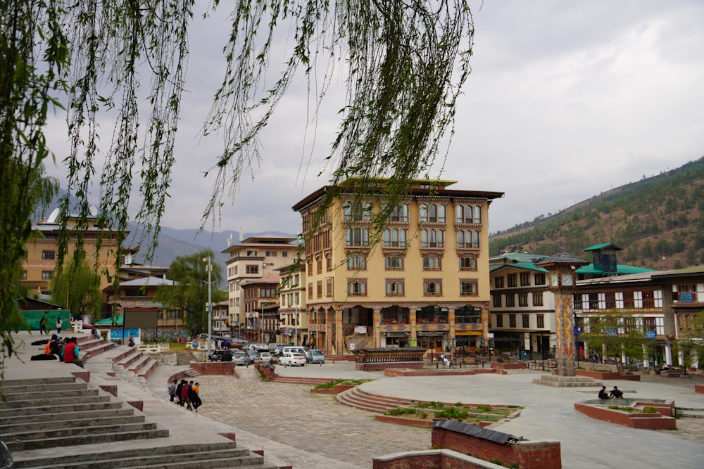 a group of buildings with trees and a river in the background