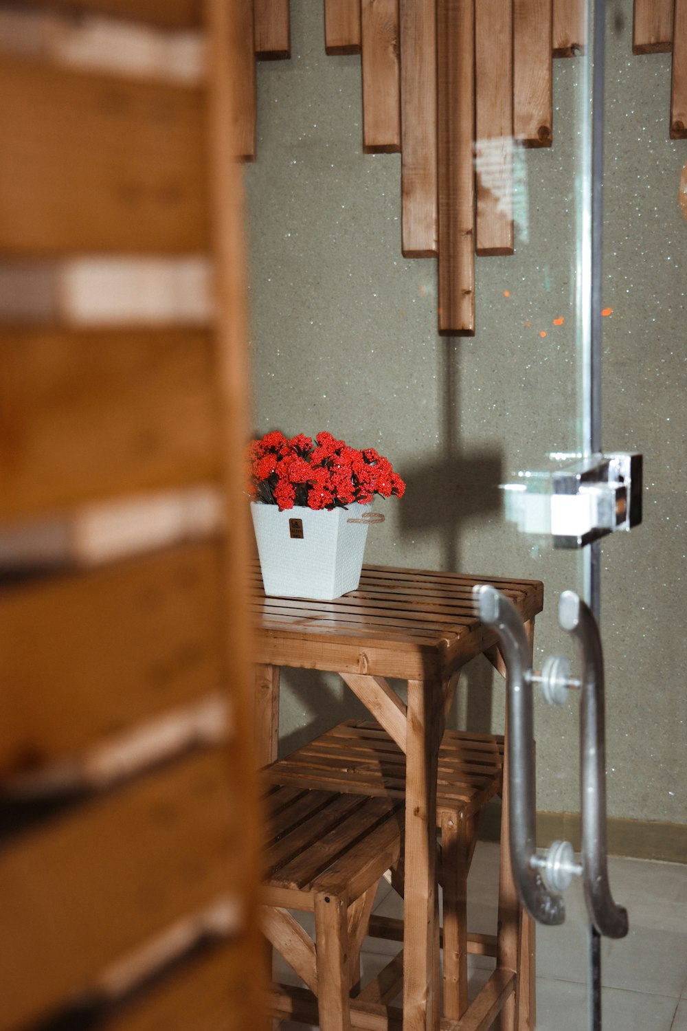 a pot of red flowers on a wooden table