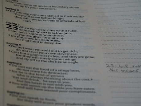 A page of text featuring biblical proverbs with sayings numbered prominently on the left side. The text discusses dining with rulers, avoiding gluttony, and the deceitfulness of riches. Handwritten notes are visible in the margins on the right.