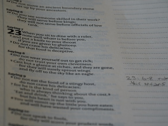 A page of text featuring biblical proverbs with sayings numbered prominently on the left side. The text discusses dining with rulers, avoiding gluttony, and the deceitfulness of riches. Handwritten notes are visible in the margins on the right.