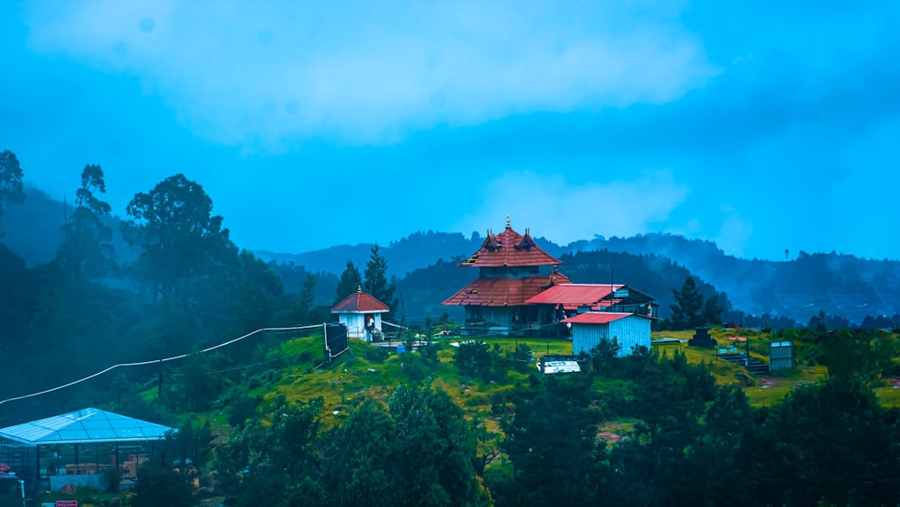 a building with a red roof surrounded by trees and mountains