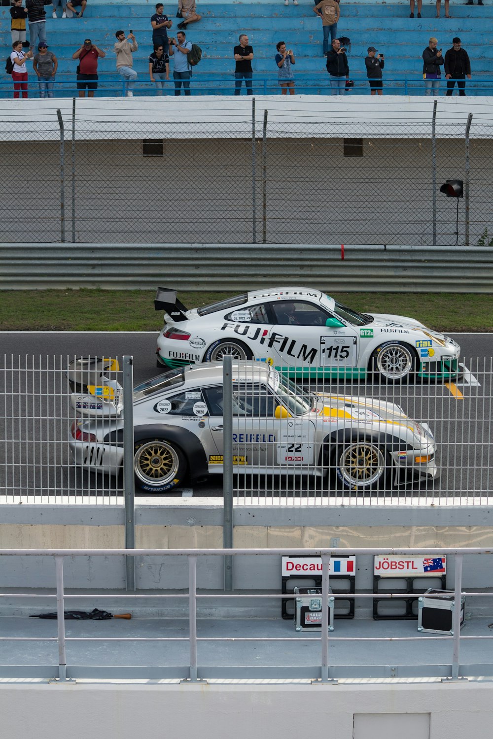 Un par de coches de carreras en una pista con gente mirando