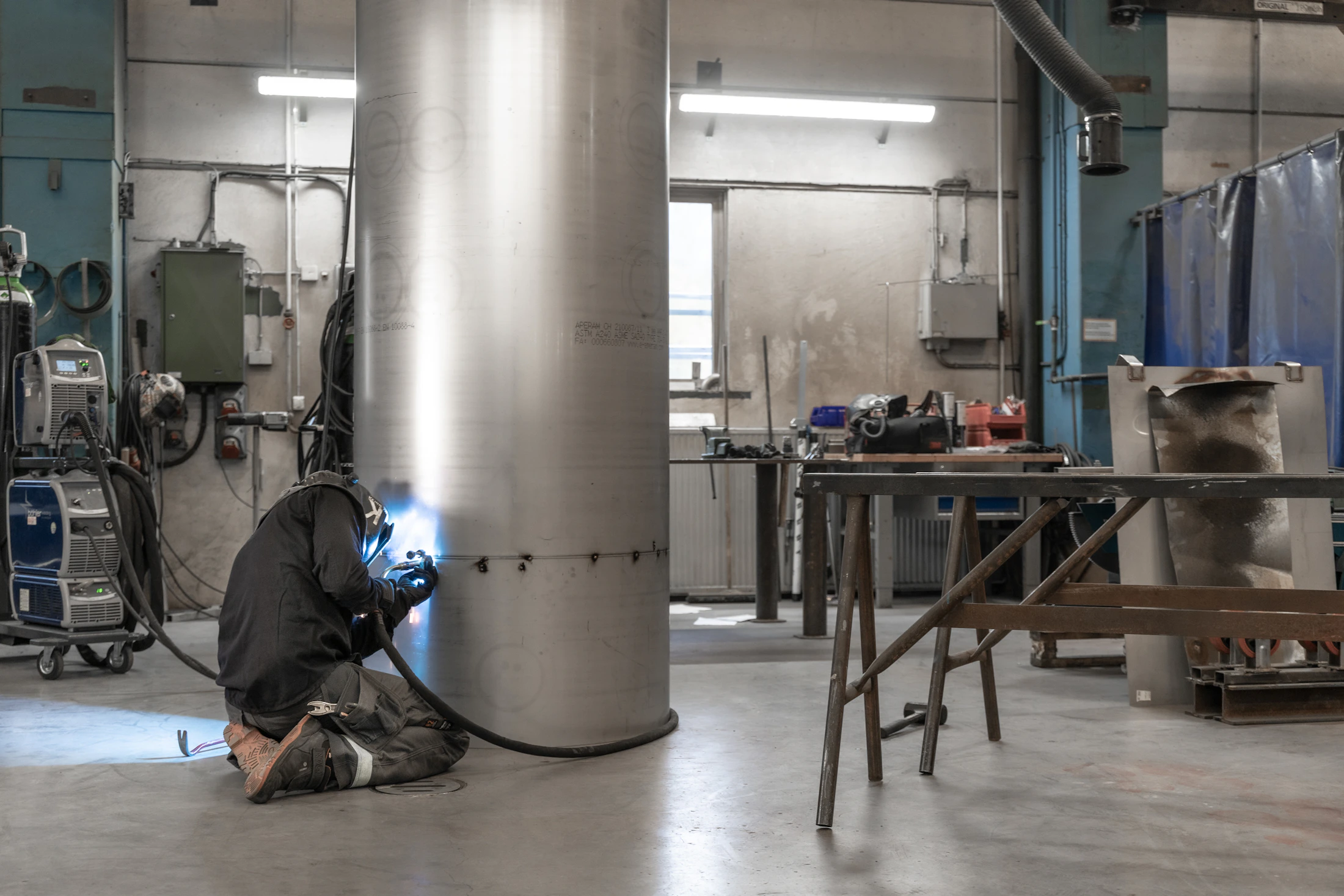 Industrial specialist working on a large metal structure inside a production environment