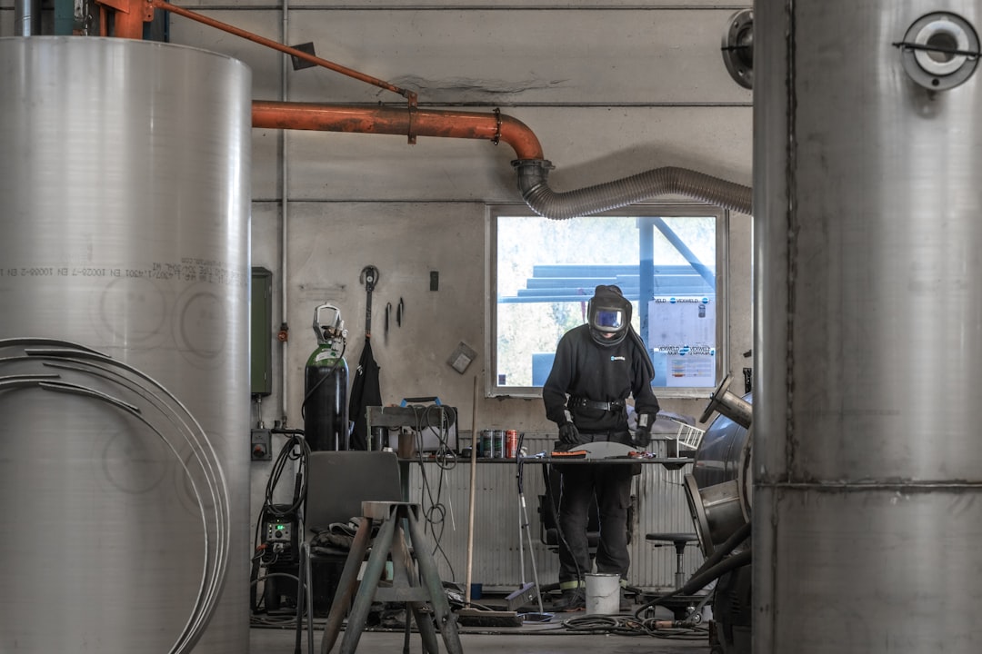 a person wearing a mask, A man in a workshop wearing a welding helmet.