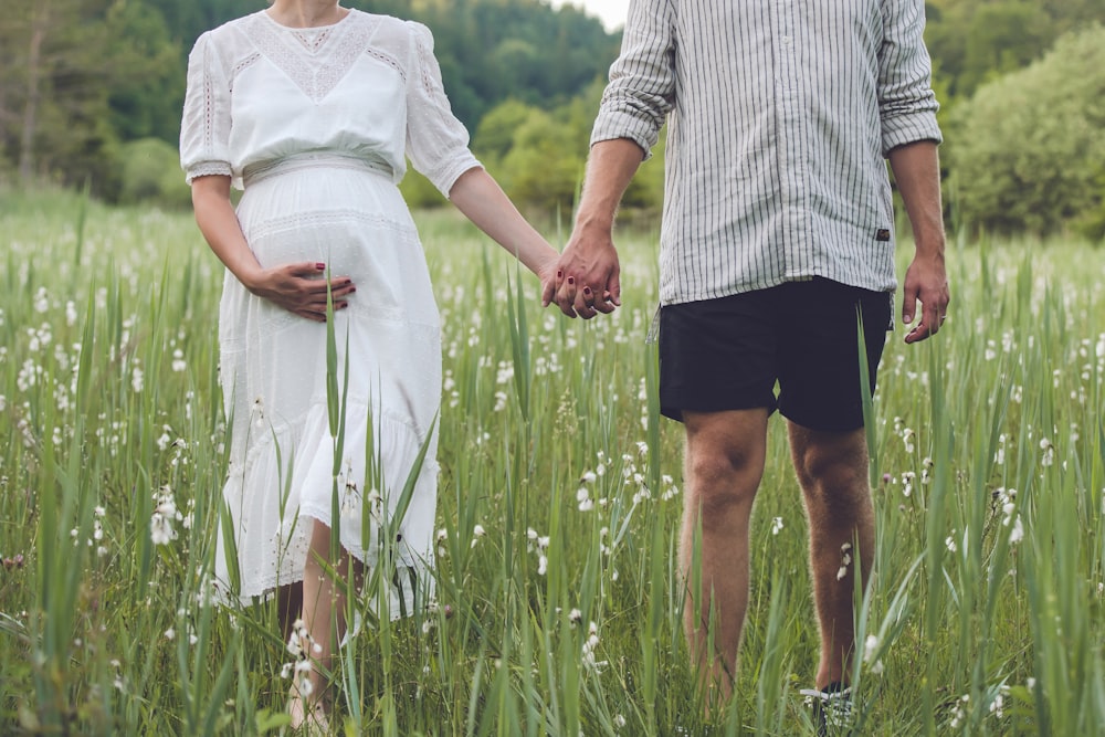 a man and woman walking in a field of grass