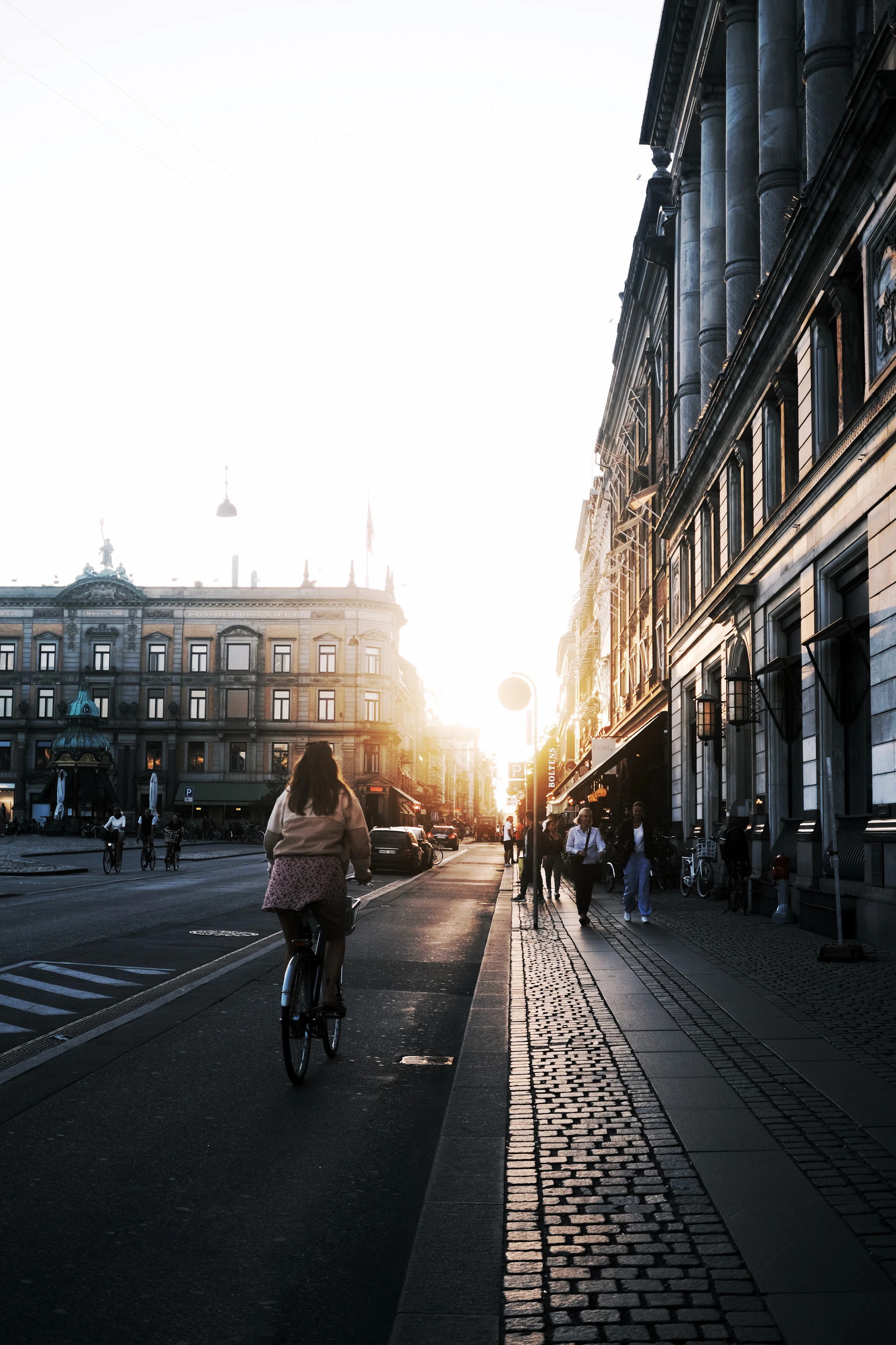 A cyclist on a broad Copenhagen street in late afternoon light
