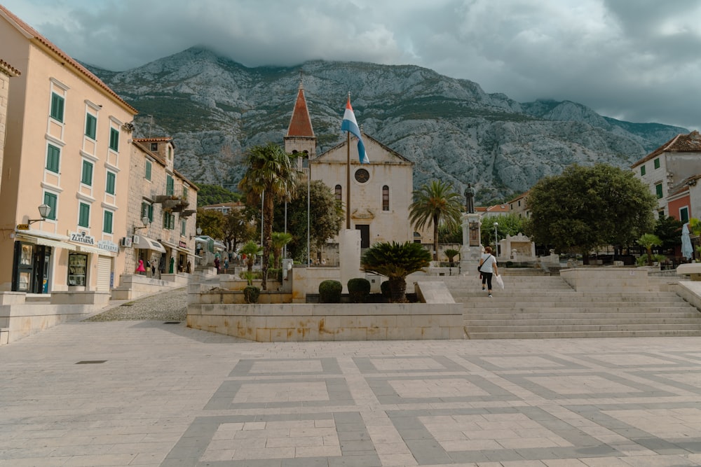 a stone courtyard with buildings and mountains in the background