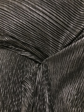 A close-up of metallic ribbed fabric showcasing fine parallel lines with a glossy texture, the surface catches light creating highlights and shadows.
