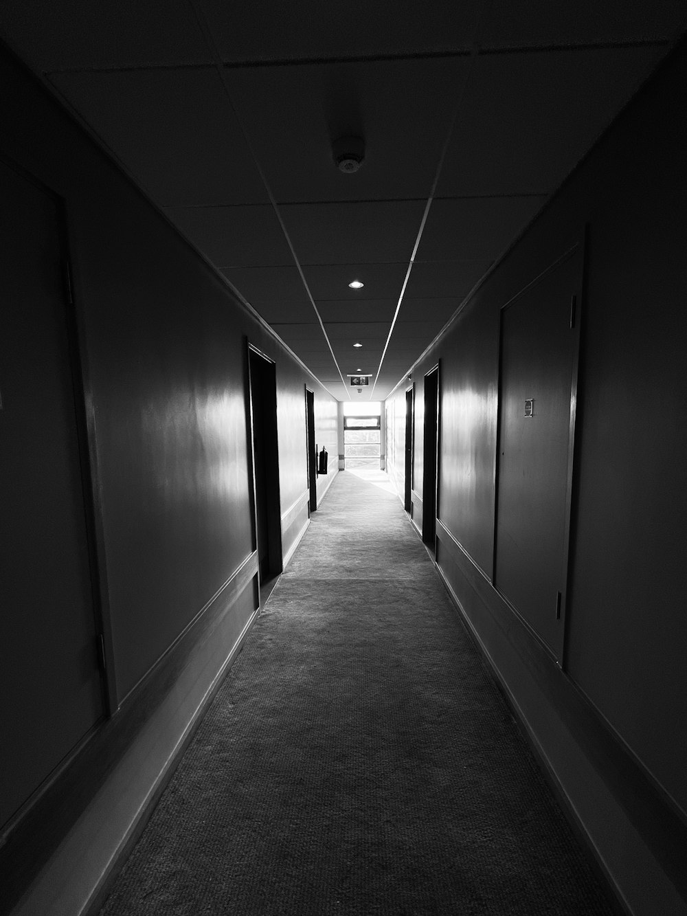 Un long couloir avec des portes noires