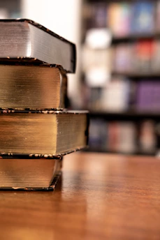Close-up of a stack of elegant academic books with a red and gold cover design on a wooden desk.