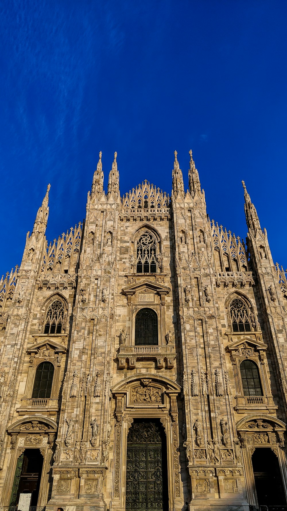 un grande edificio in pietra con il Duomo di Milano sullo sfondo