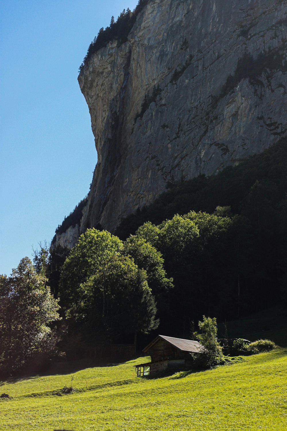 a small house in front of a large rock cliff