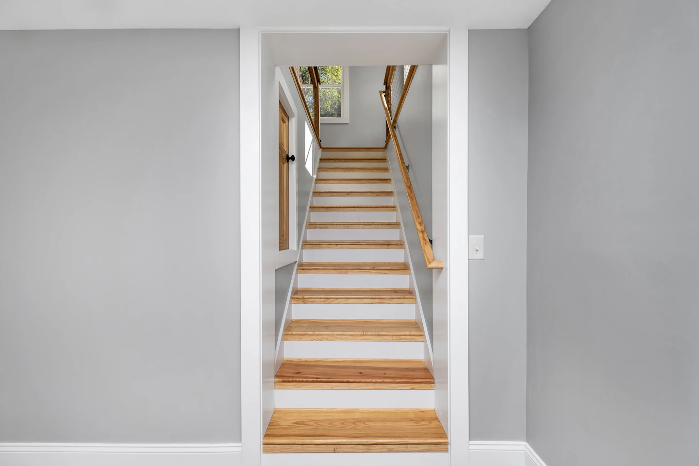 Refinished wood staircase between freshly painted walls
