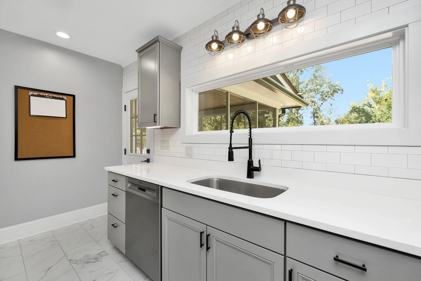 Kitchen sink with a black faucet under a wide window