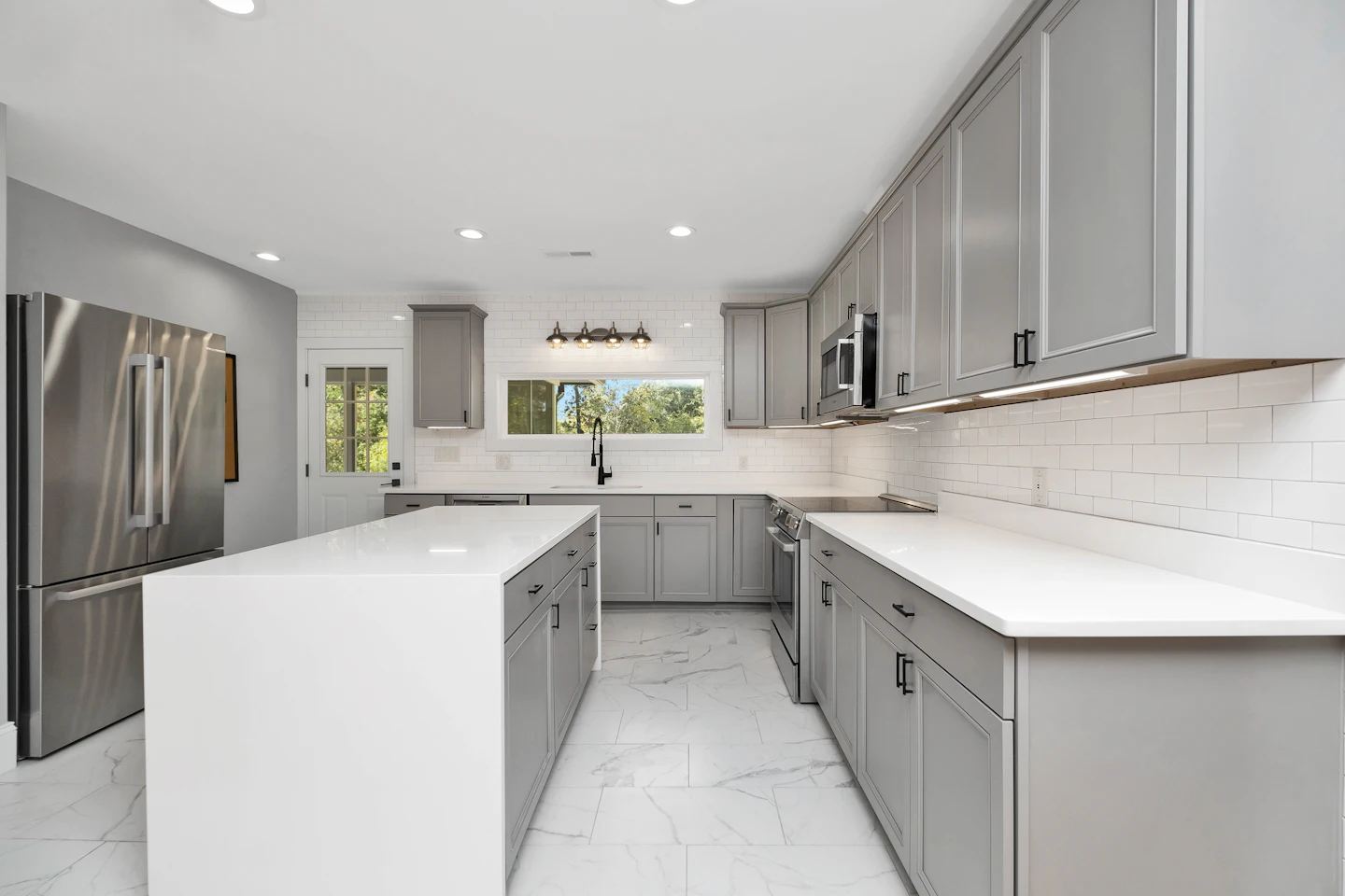 Gray and white kitchen with stainless appliances and quartz counters