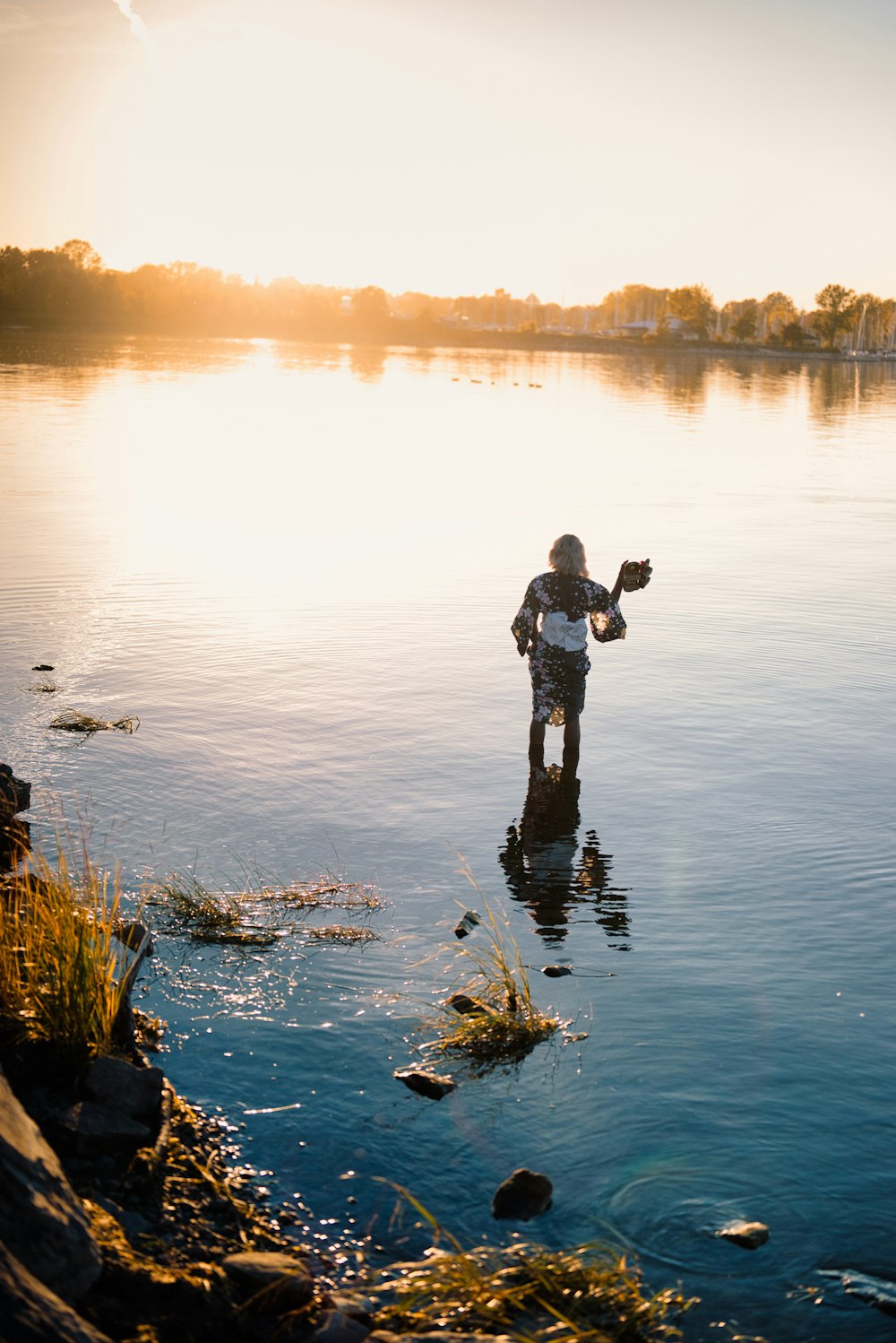 a person standing in a body of water with trees in the background