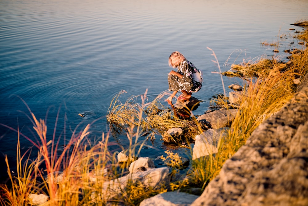 a person sitting on a rock in the water