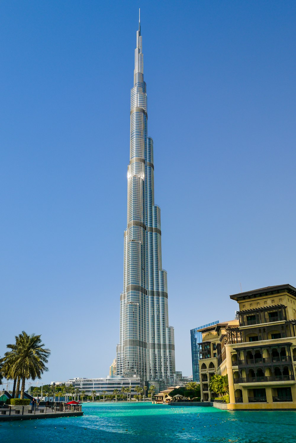 a tall building with a pool in front of it with Burj Khalifa in the background