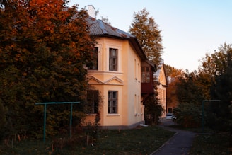 Front view of a cozy two-story house with a small garden and warm lighting at sunset.