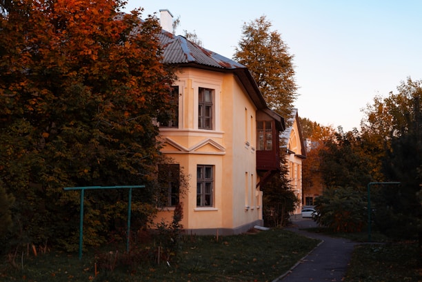 Front view of a cozy two-story house with a small garden and warm lighting at sunset.