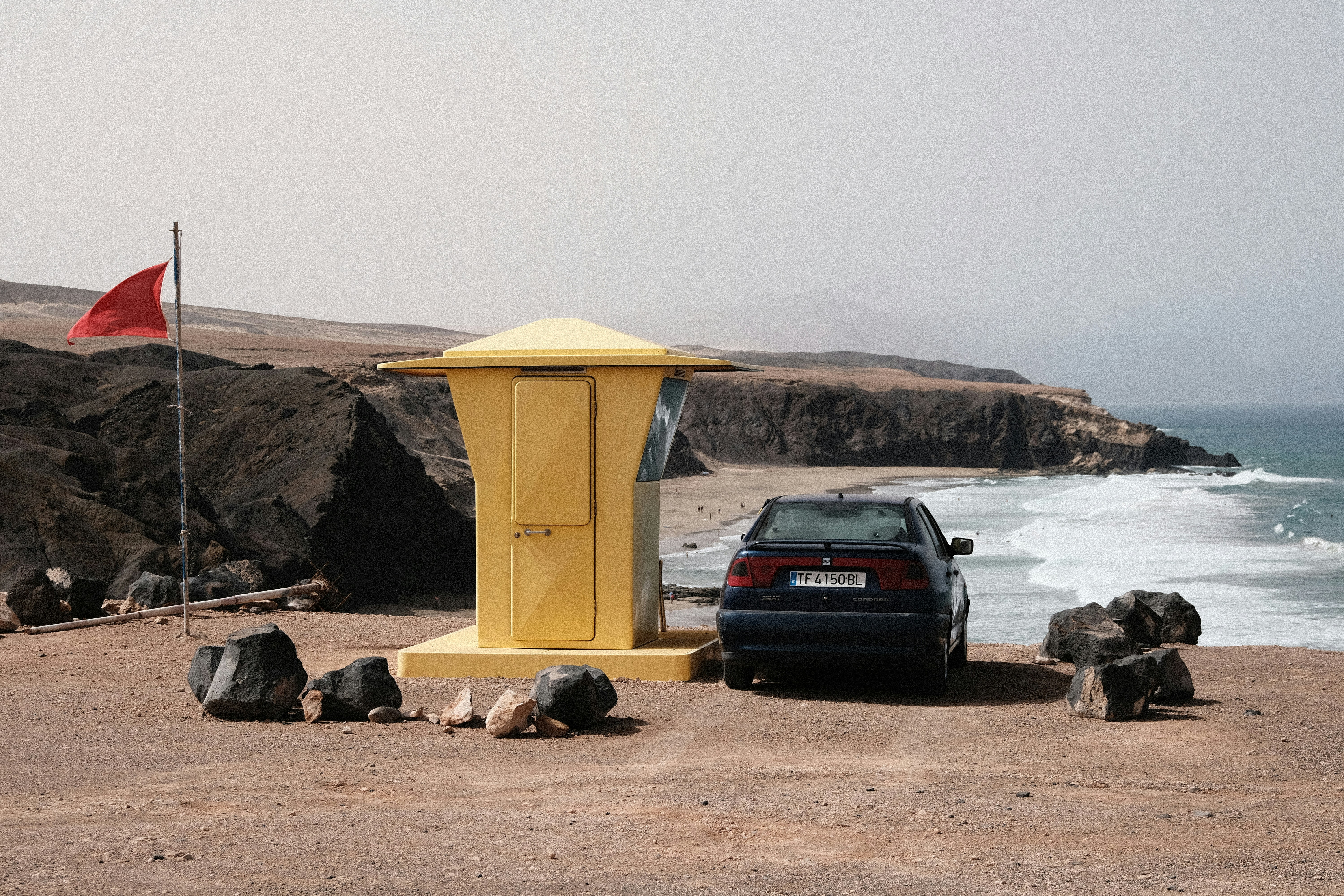 a car parked next to a yellow structure on a beach