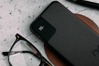 A compact power bank with a glowing LED indicator, charging a smartphone on a cozy desk setup.
