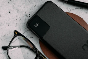 A compact power bank with a glowing LED indicator, charging a smartphone on a cozy desk setup.