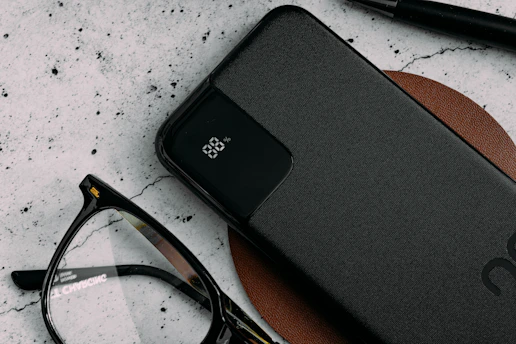 Sleek silver power bank angled on a dark blue surface with subtle lighting highlighting its smooth edges.