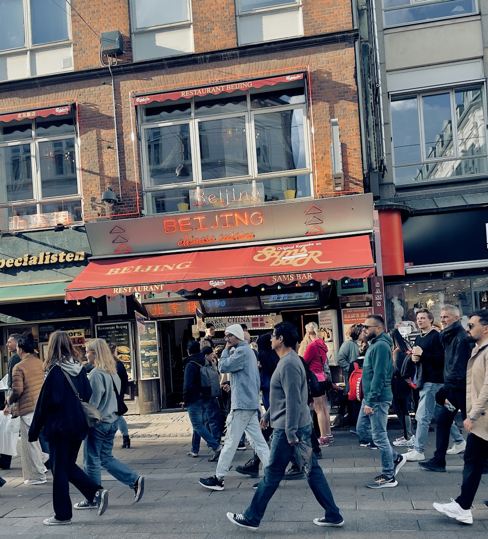 a group of people walking on a sidewalk next to a building