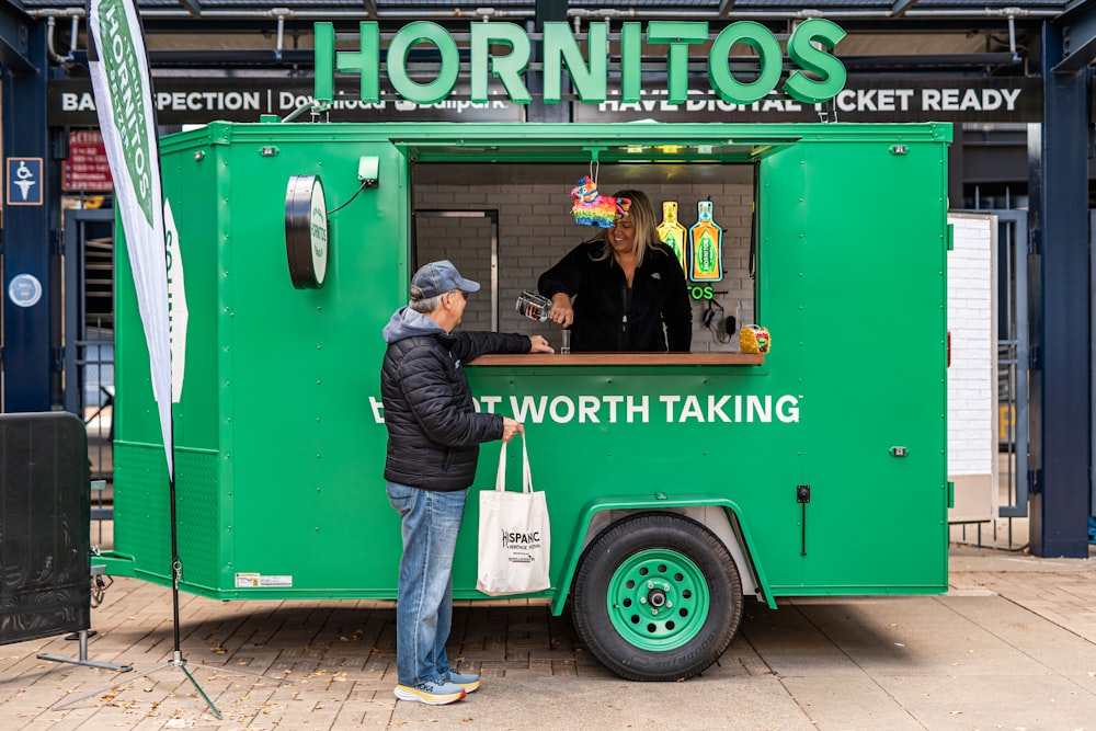 a person standing next to a green food truck