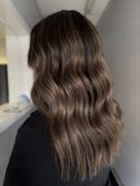 Close-up of shiny, wavy brunette hair cascading over shoulders.