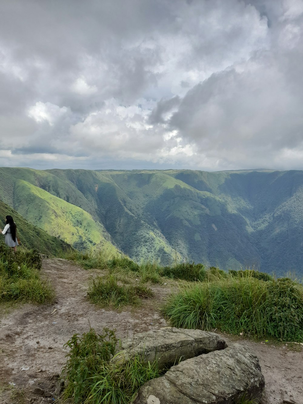 a person walking on a dirt path in a hilly landscape