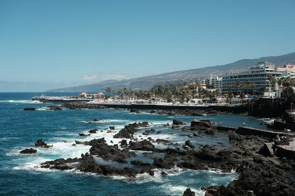 a rocky beach with buildings and water