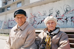a man and woman standing in front of a wall with graffiti