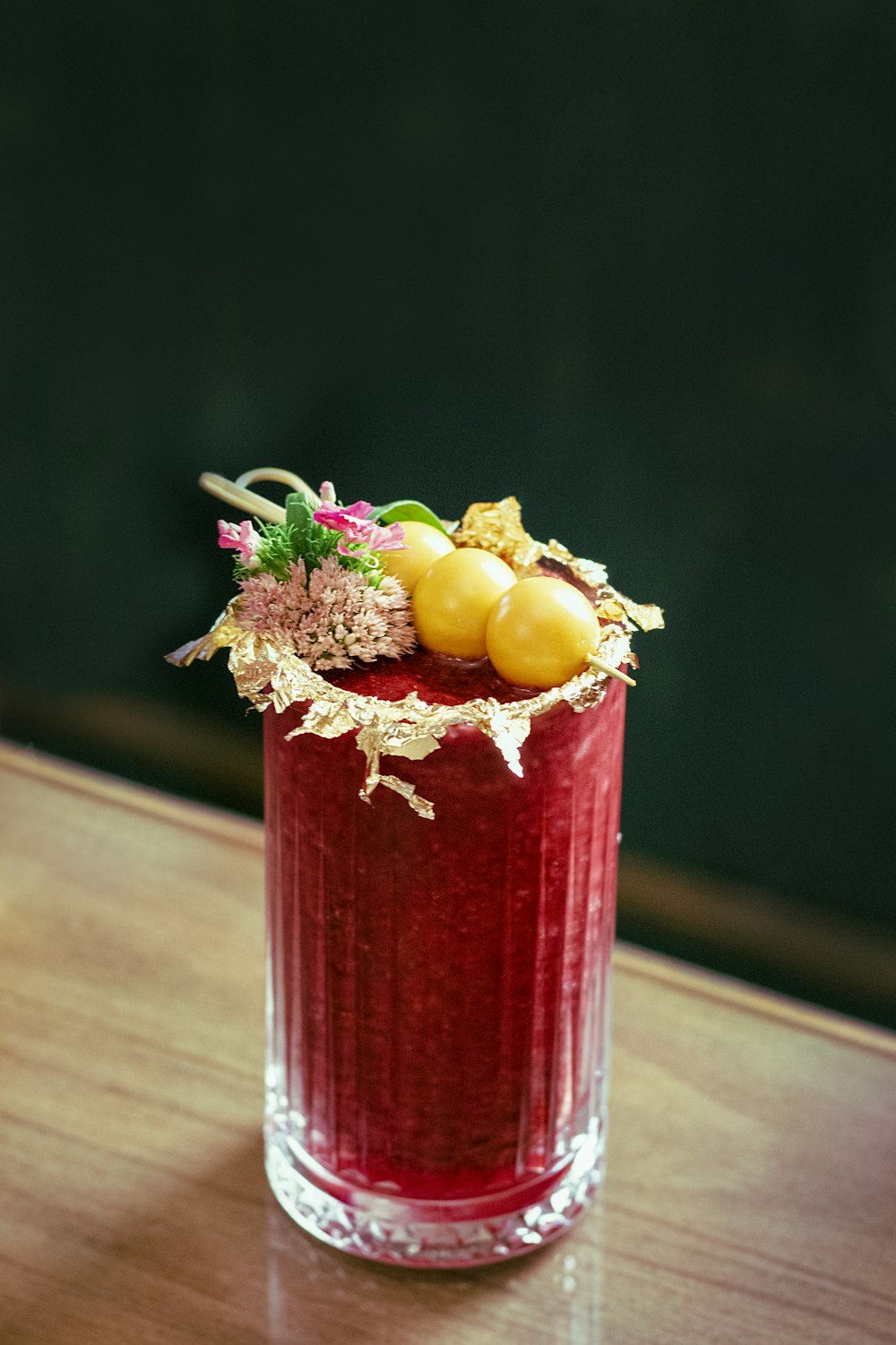 a glass of orange juice next to a vase of flowers on a table