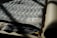 A folded textile piece made from 100% organic cotton with a geometric chevron pattern. The label, indicating it's from towel studio and made in Germany, is visible. The fabric appears to be draped on a flat surface, with one edge slightly in shadow.
