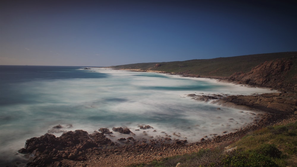 a body of water with rocks and grass on the side