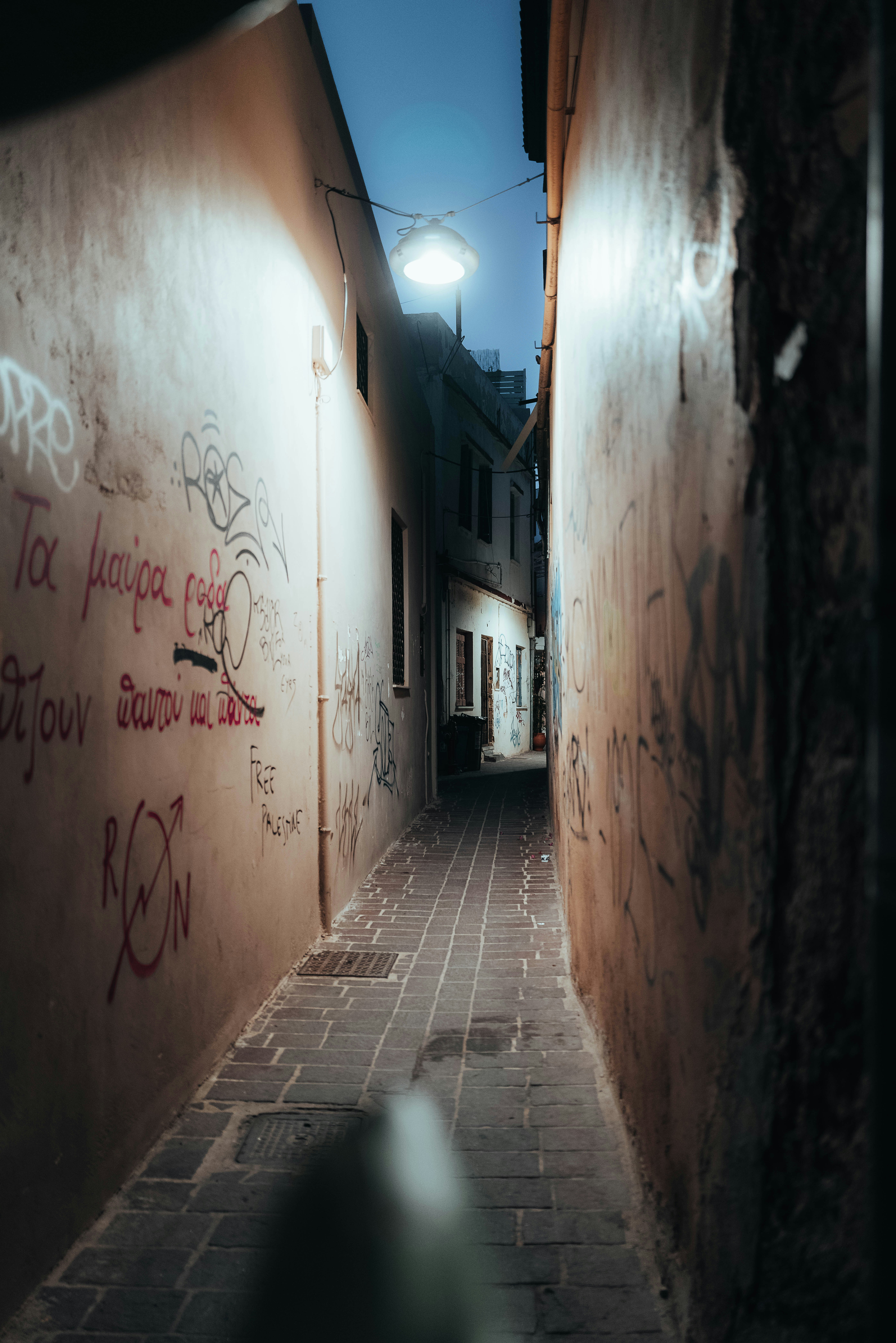a narrow hallway with graffiti on the side of a building