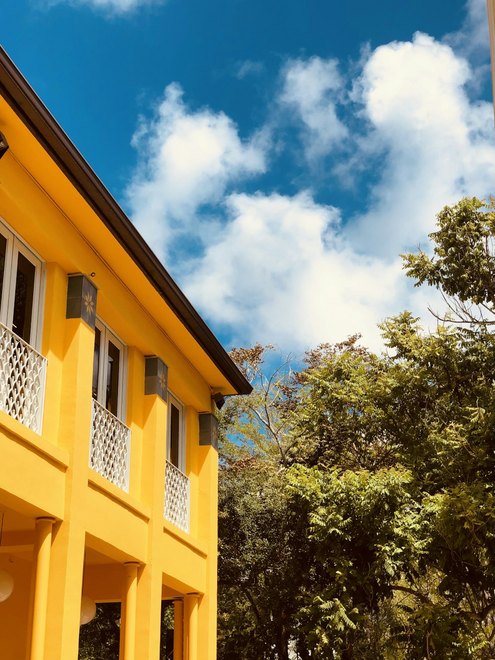 a yellow building with trees in the background
