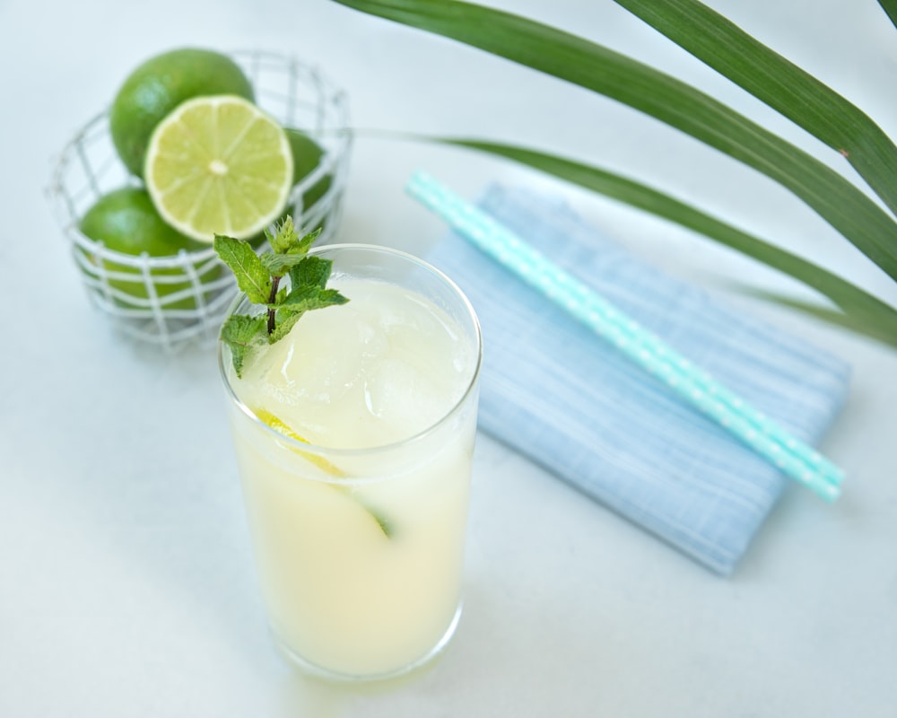 a glass of lemonade with limes and a slice of lime