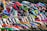 A group of motocross riders lined up, each wearing colorful helmets and gear. Their motorcycles are vibrant and varied in design, highlighting the diversity of the sport. The scene is dynamic, full of energy and anticipation.