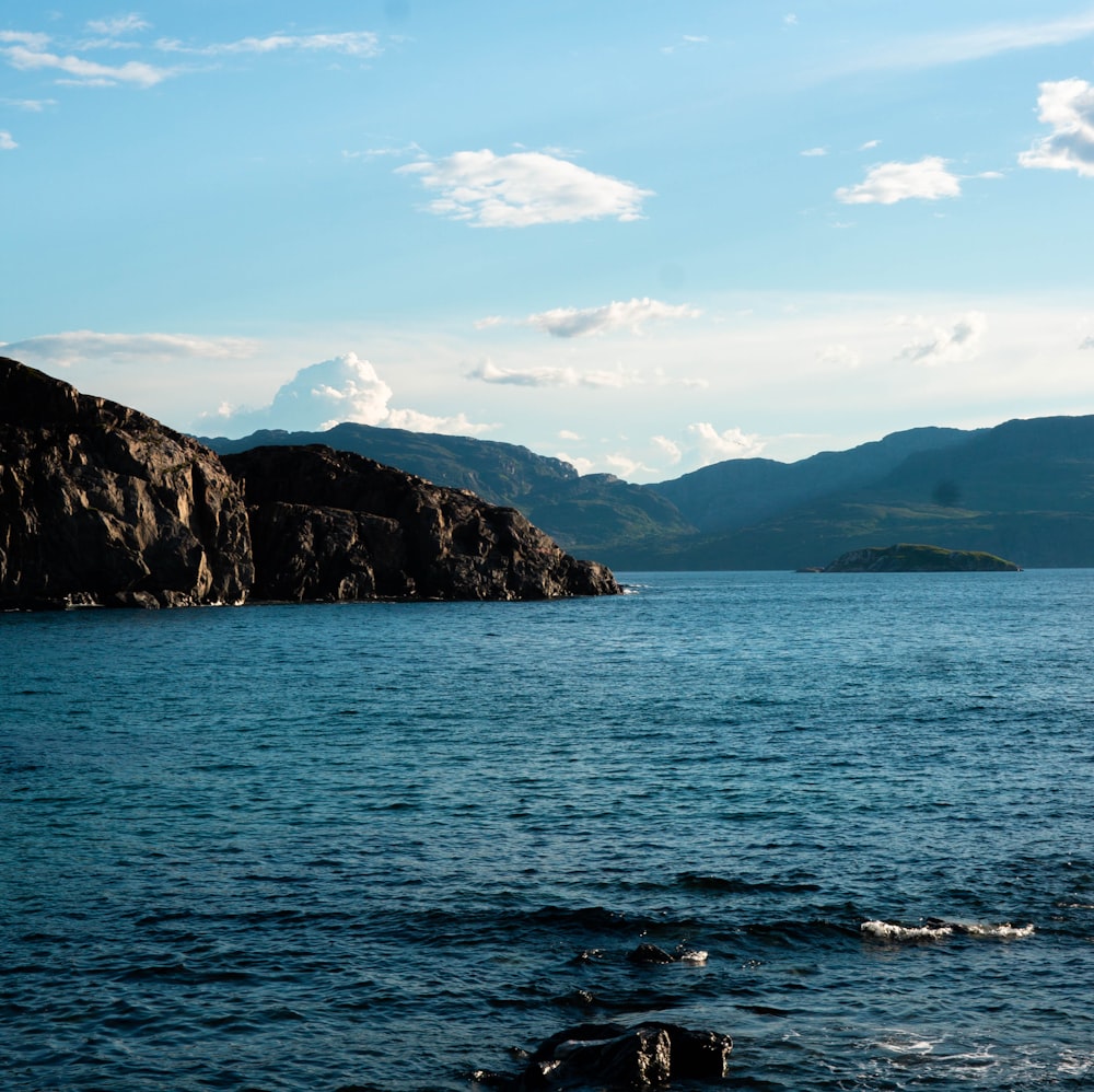 a body of water with a rocky shoreline and blue sky