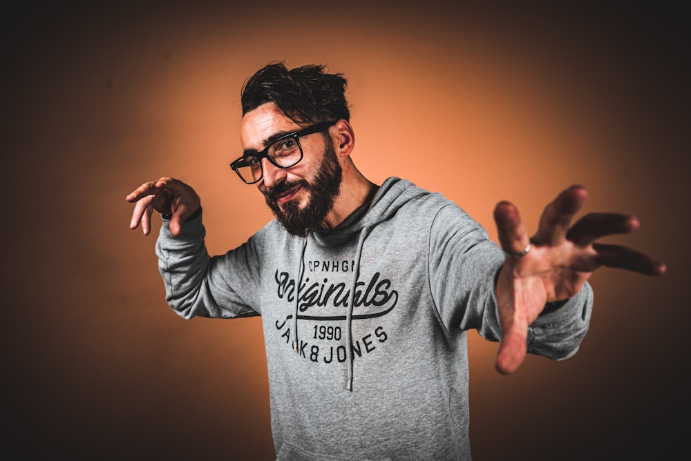 a man with glasses and a beard holding his hands up