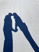 Close-up of intertwined human hands casting sharp shadows on a slate surface.