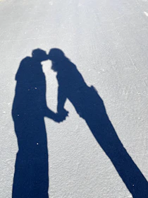 An intimate candid of a couple holding hands, shadows playing softly on their faces.