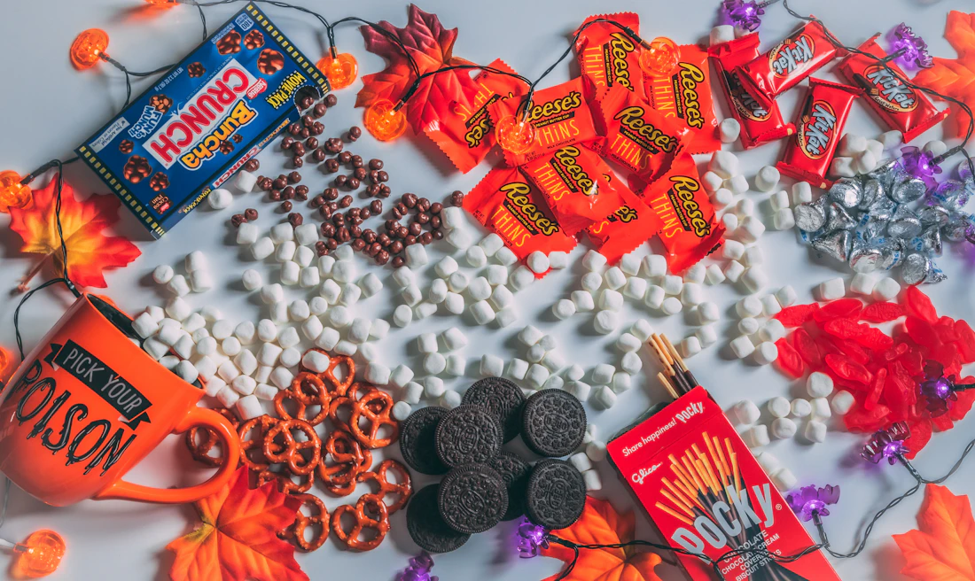Halloween candy and chocolate scattered among fall leaves