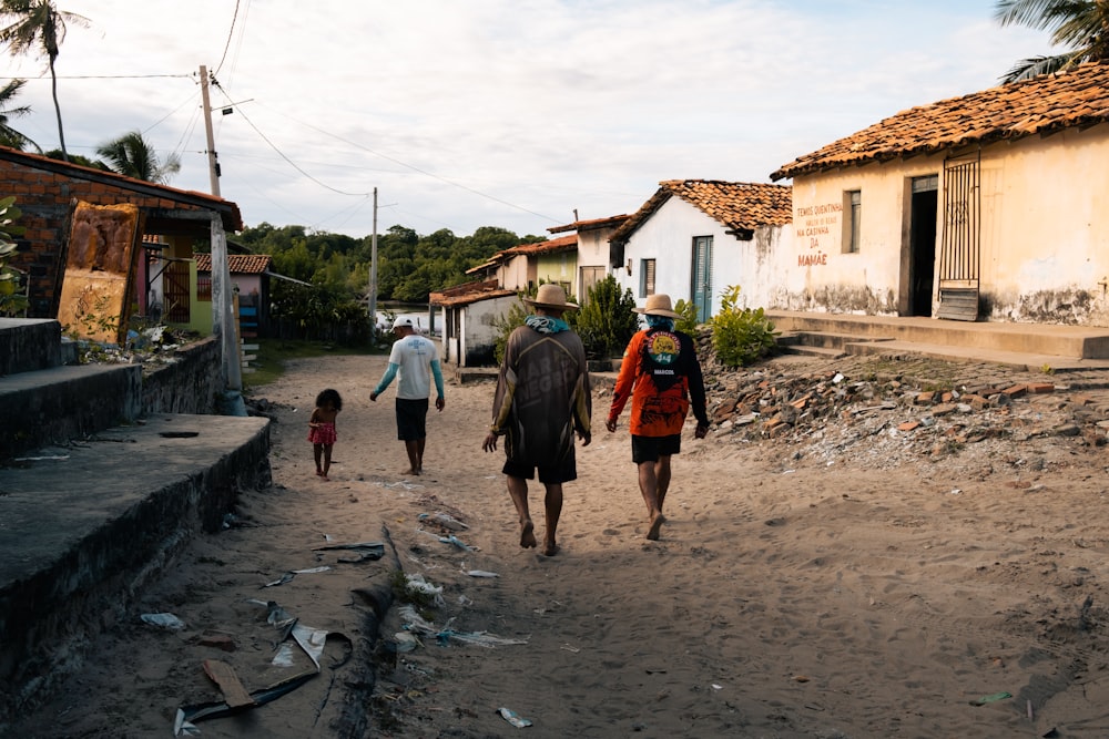 um grupo de pessoas andando em uma estrada de terra entre os edifícios