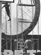 Workers setting up scaffolding ladders at an industrial site.